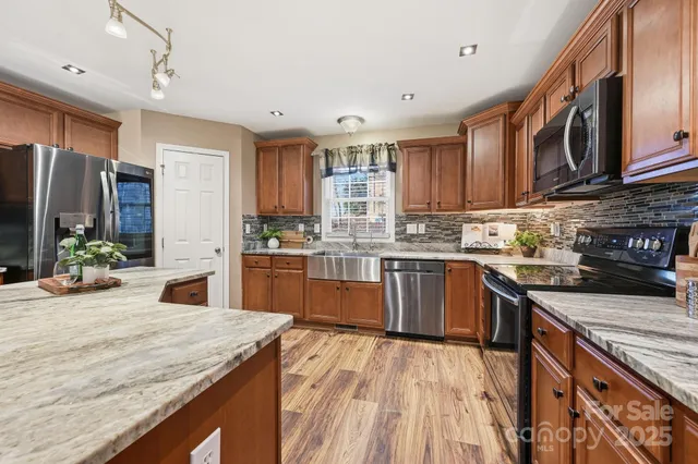a kitchen with stainless steel appliances granite countertop a stove refrigerator sink and cabinets