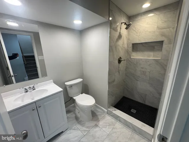 a bathroom with a sink a toilet a mirror and shower