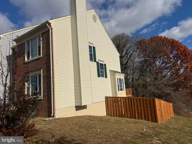 a view of a house with wooden fence and large trees