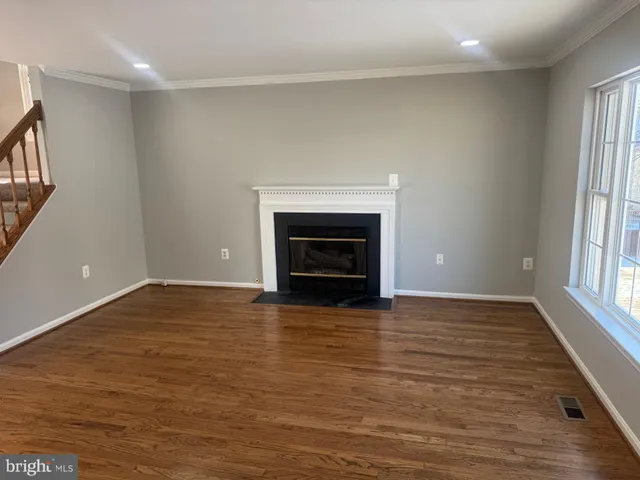 a view of empty room with wooden floor and fireplace