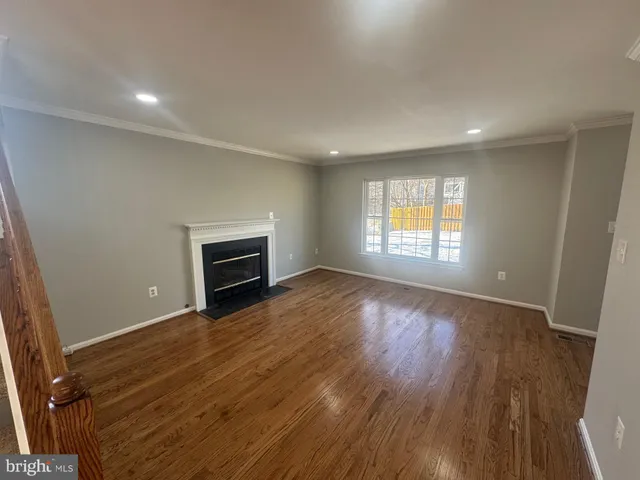 an empty room with wooden floor fireplace and windows