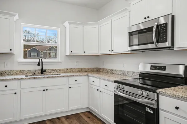 a kitchen with granite countertop white cabinets and stainless steel appliances