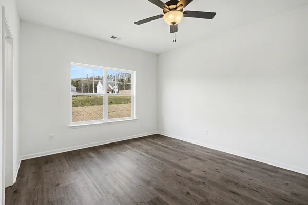 an empty room with wooden floor fan and windows