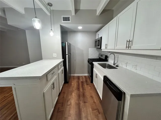 a kitchen with white cabinets sink and stainless steel appliances
