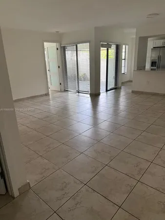 an empty room with large windows and a way to kitchen