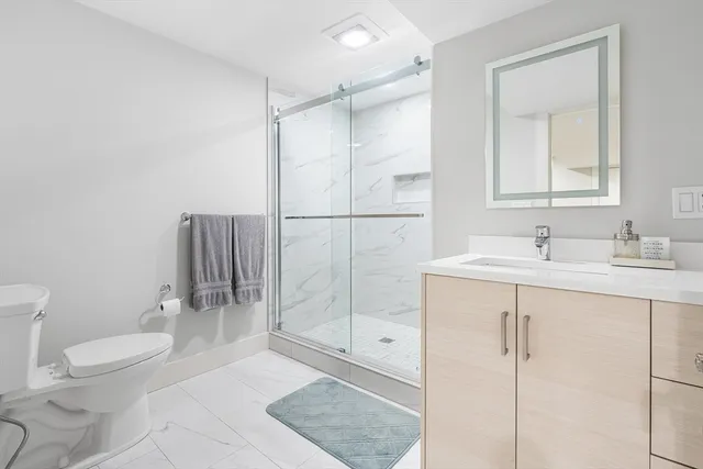 a bathroom with a shower sink mirror and toilet