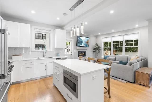 a large white kitchen with cabinets a sink a stove a dining table and chairs