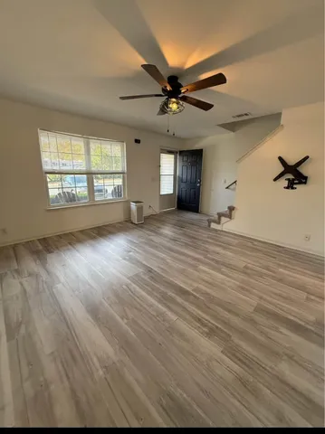 an empty room with windows and ceiling fan