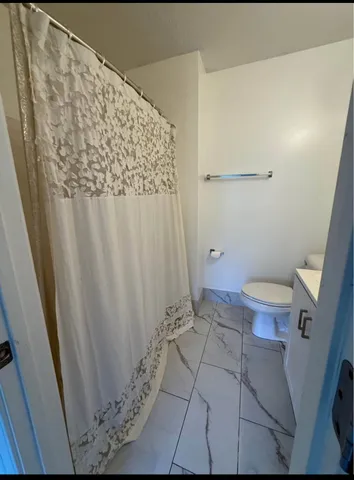 a bathroom with a toilet and a shower curtain