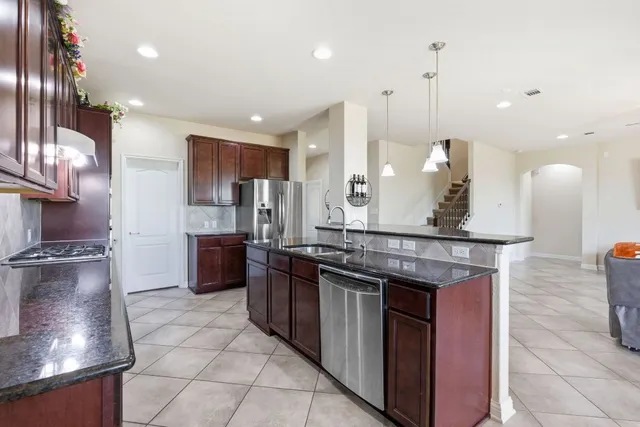 a kitchen with stainless steel appliances granite countertop a stove a sink and a refrigerator