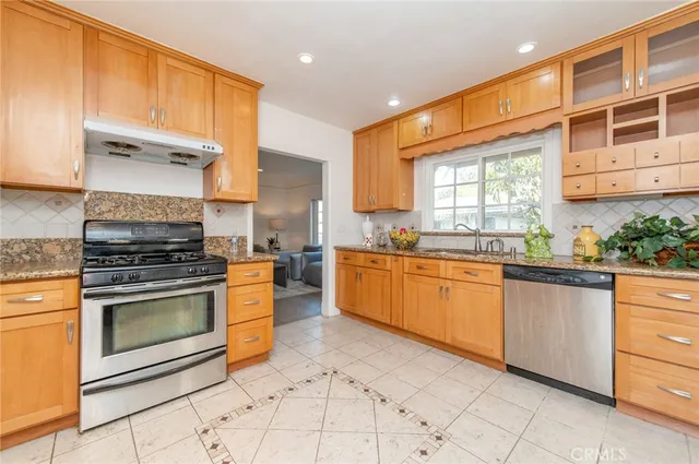 a kitchen with stainless steel appliances granite countertop a stove a sink and a microwave