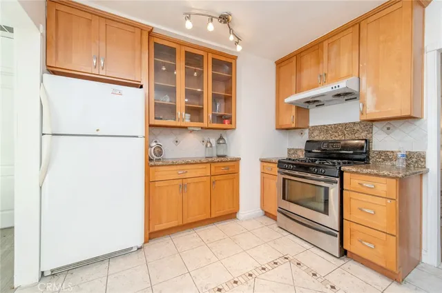 a kitchen with stainless steel appliances granite countertop a refrigerator sink stove and cabinets
