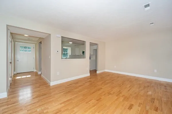 a view of an empty room with wooden floor and a window