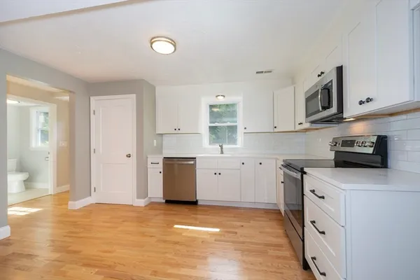 a kitchen with stainless steel appliances a sink a stove a table and chairs