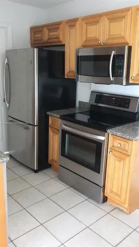 a kitchen with granite countertop a stove top oven microwave and refrigerator