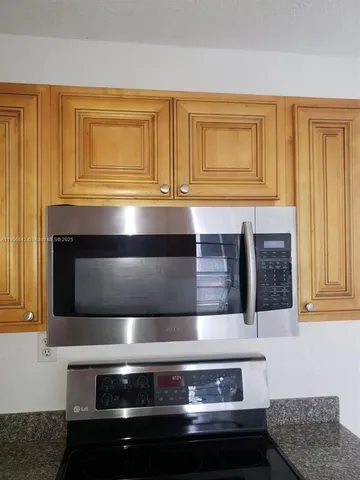 a kitchen with granite countertop stove top oven and cabinets