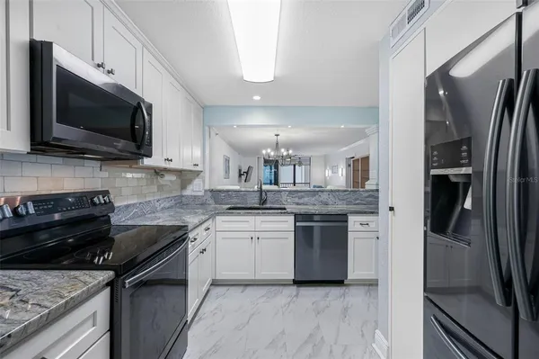 a kitchen with granite countertop white cabinets sink and stainless steel appliances