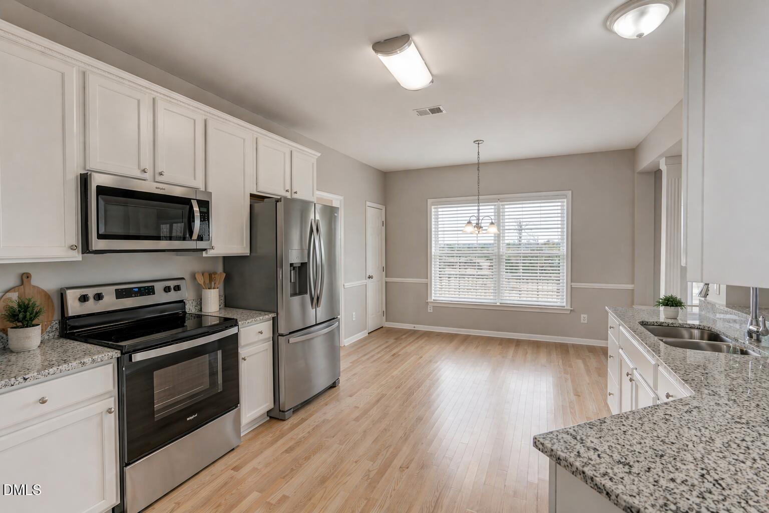 480 Seastone Street Raleigh, NC 27603 - Photo 5 of 26 a kitchen with granite countertop a stove a sink dishwasher a refrigerator and a microwave oven with wooden floor