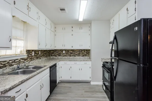a kitchen with stainless steel appliances granite countertop a refrigerator a sink and white cabinets