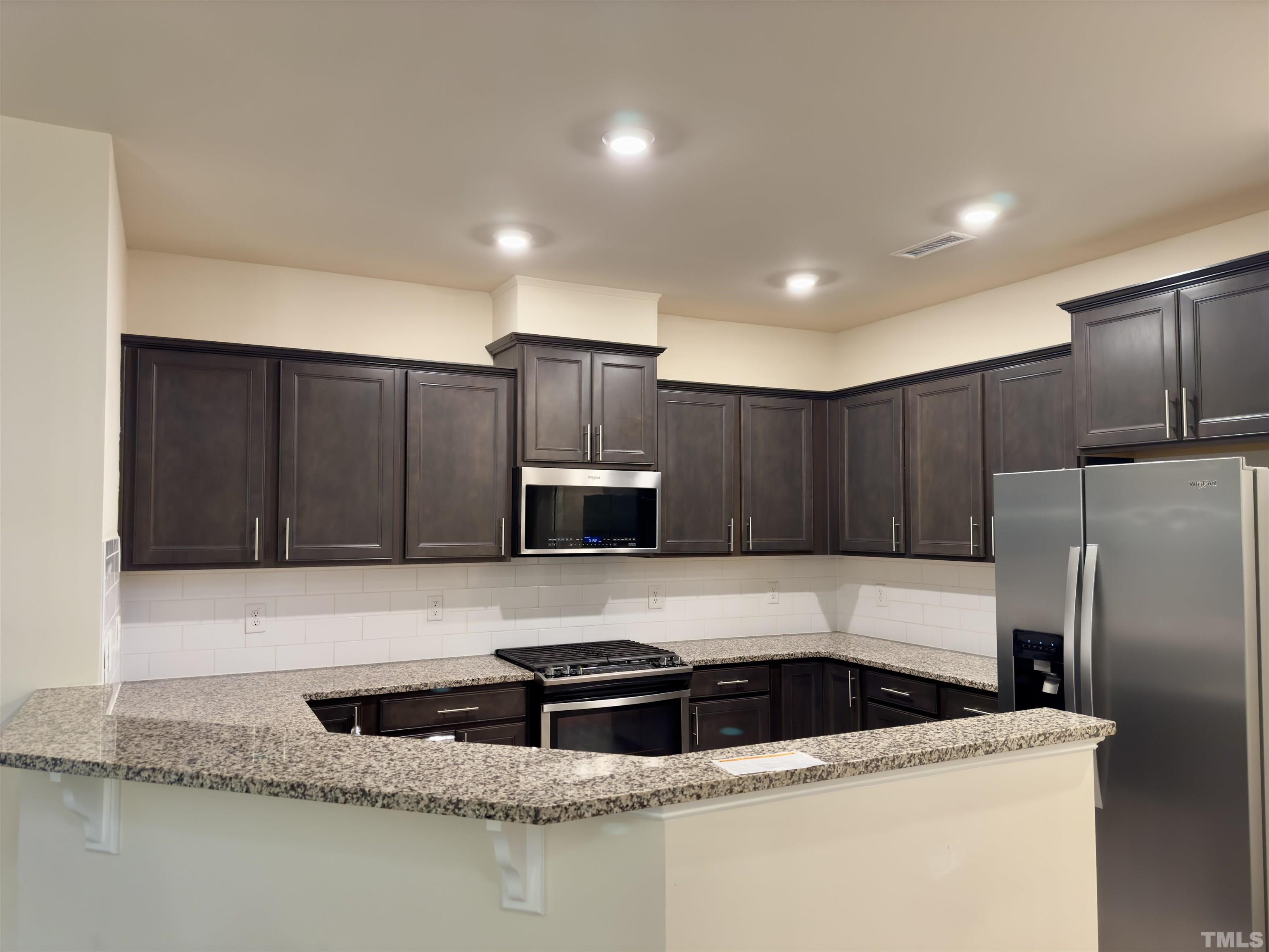 33 Rambler Lane Durham, NC 27703 - Photo 11 of 36 a kitchen with granite countertop a sink a refrigerator and a stove top oven with wooden floor