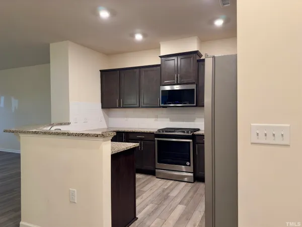 a kitchen with stainless steel appliances granite countertop a stove a refrigerator and a microwave