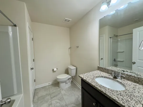 a bathroom with a granite countertop sink toilet and shower