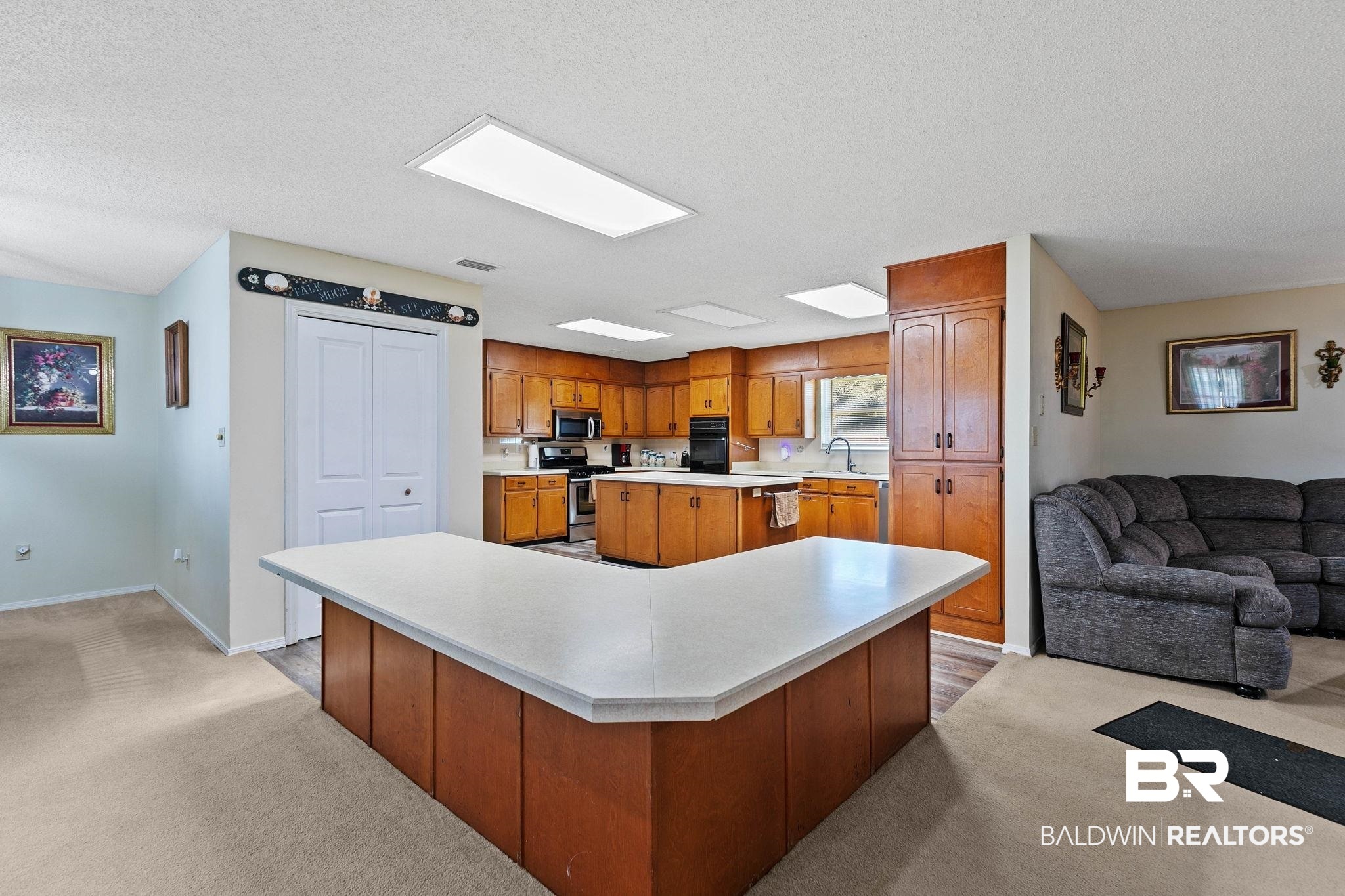 1510 South Juniper Street Foley, AL 36535 - Photo 36 of 36 Kitchen with light countertops, light colored carpet, a kitchen island, open floor plan, and a textured ceiling