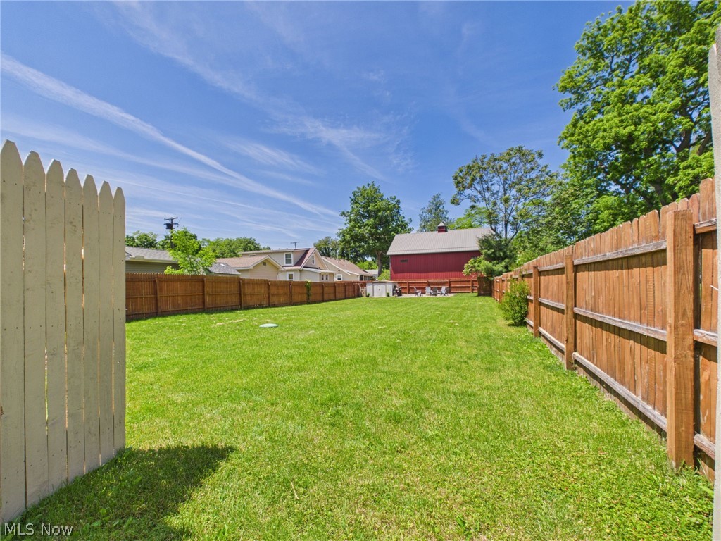 3490 County Line Road Madison, OH 44057 - Photo 13 of 42 Expansive green lawn framed by a privacy fence, featuring a white picket gate and a stained wood fence