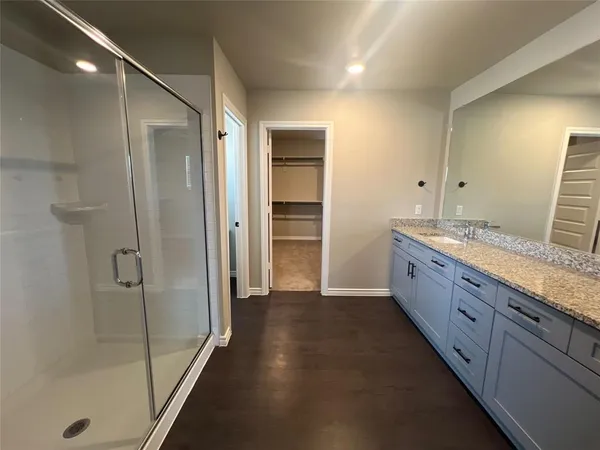 a bathroom with a granite countertop sink a mirror and a shower