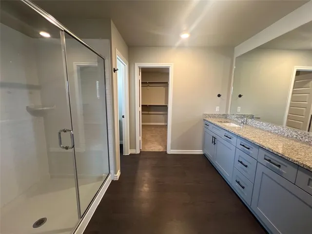 a bathroom with a granite countertop sink a mirror and a shower