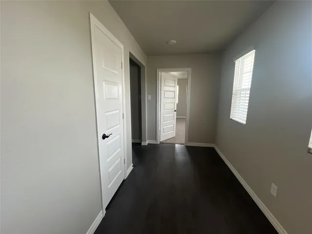 a view of hallway with window and wooden floor