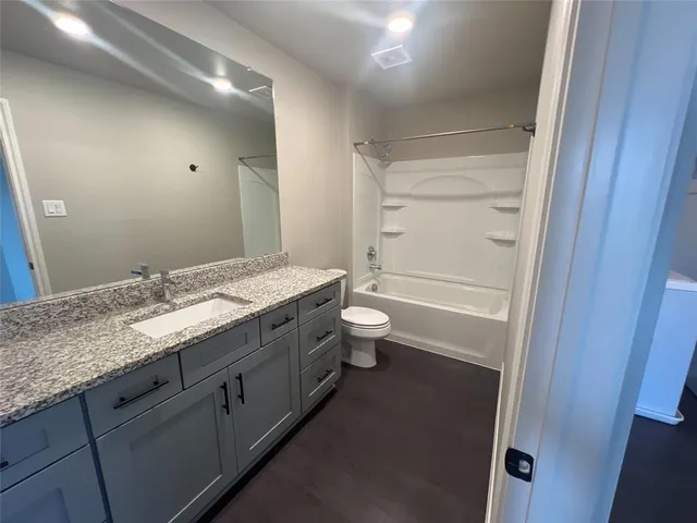 a bathroom with a granite countertop sink a toilet and shower