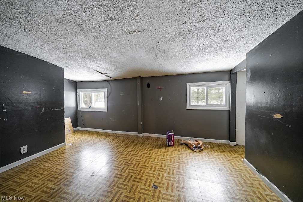 9606 Durst Colebrook Road North Bloomfield, OH 44450 - Photo 6 of 24 Unfurnished room with light parquet flooring, a textured ceiling, and a healthy amount of sunlight