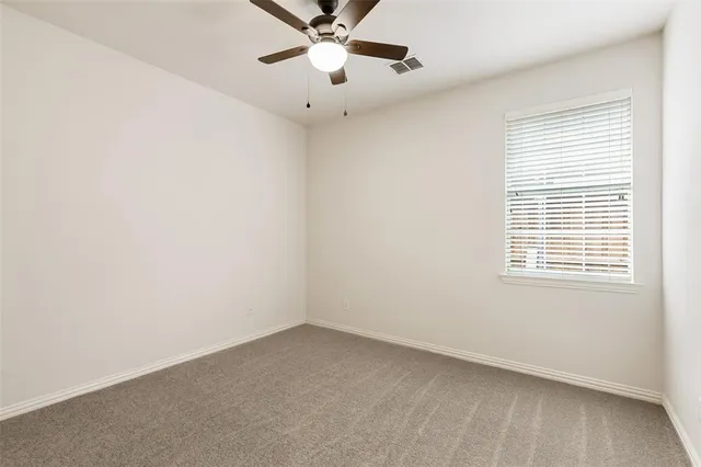 an empty room with a window and ceiling fan