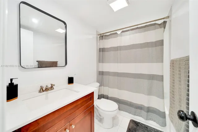 a bathroom with a sink a toilet a mirror and shower