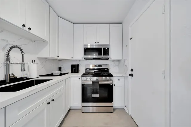 a kitchen with stainless steel appliances granite countertop white cabinets and black stove top oven with granite countertops