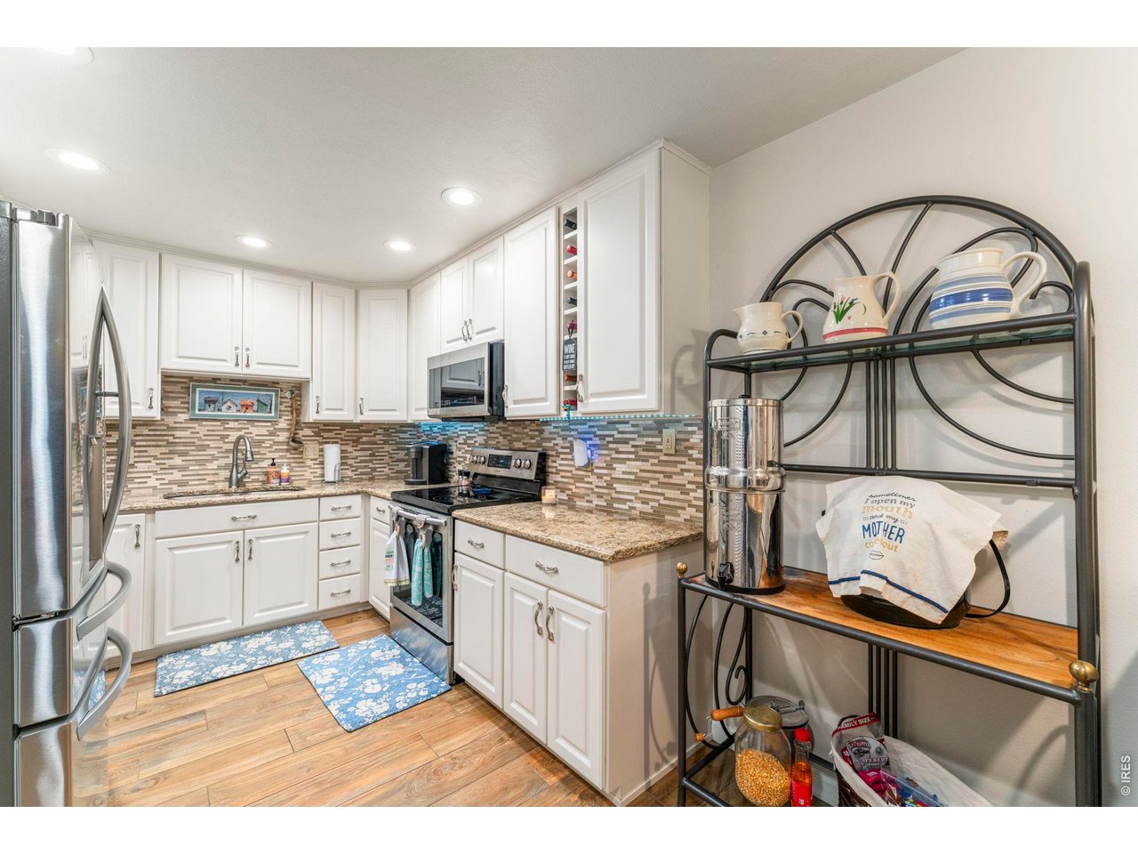 39 Ward Drive, Unit 104 Greeley, CO 80634 - Photo 14 of 31 a kitchen with stainless steel appliances granite countertop a stove top oven a sink dishwasher and white cabinets with wooden floor