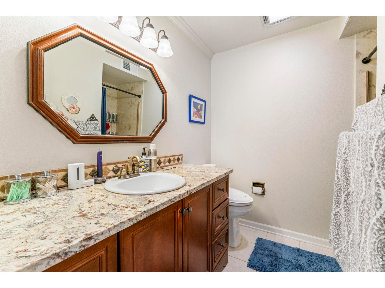 39 Ward Drive, Unit 104 Greeley, CO 80634 - Photo 20 of 31 a bathroom with a granite countertop sink a mirror and a toilet