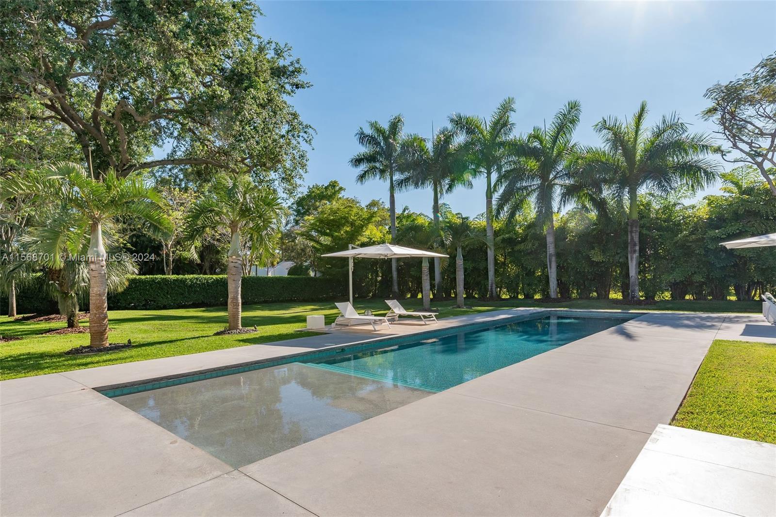 6795 Southwest 113th Street Pinecrest, FL 33156 - Photo 21 of 30 a view of a swimming pool with a yard and palm trees