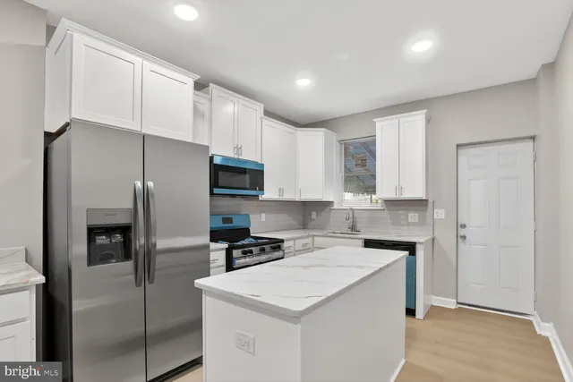 a kitchen that has a refrigerator a sink and cabinets