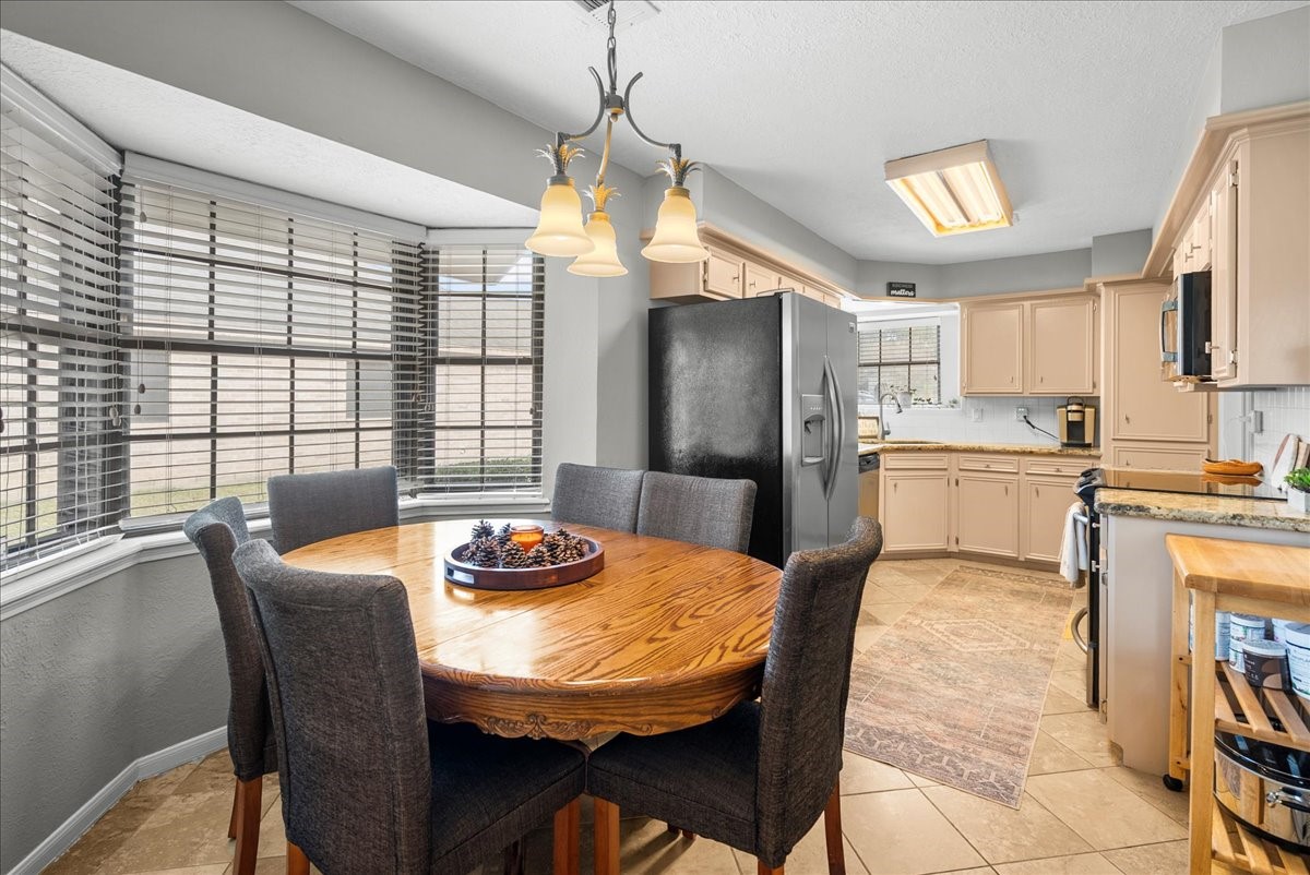 7111 Tonkawa Street Baytown, TX 77521 - Photo 10 of 23 a kitchen with granite countertop a refrigerator a sink dishwasher a dining table and chairs with wooden floor