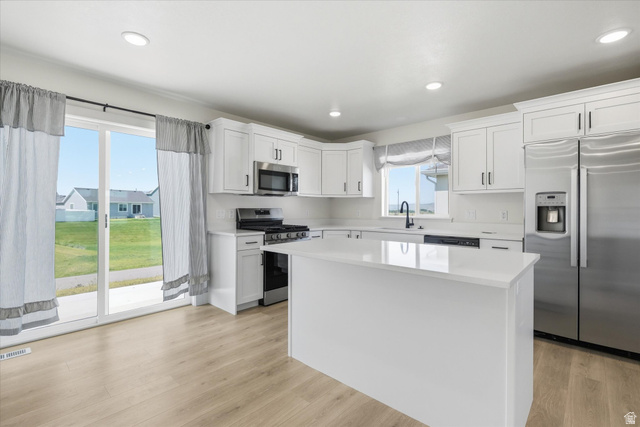 730 West 500 North Smithfield, UT 84335 - Photo 11 of 46 Kitchen featuring white cabinetry, a central island with a solid surface countertop, stainless steel appliances, and wood-finish flooring