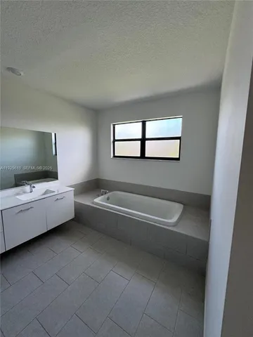 a bathroom with a double vanity sink a toilet mirror and bathtub