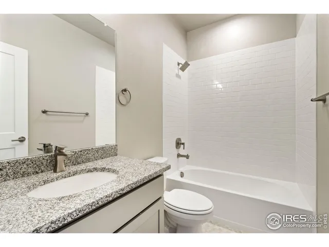 a bathroom with a granite countertop sink a toilet a mirror a bathtub and shower
