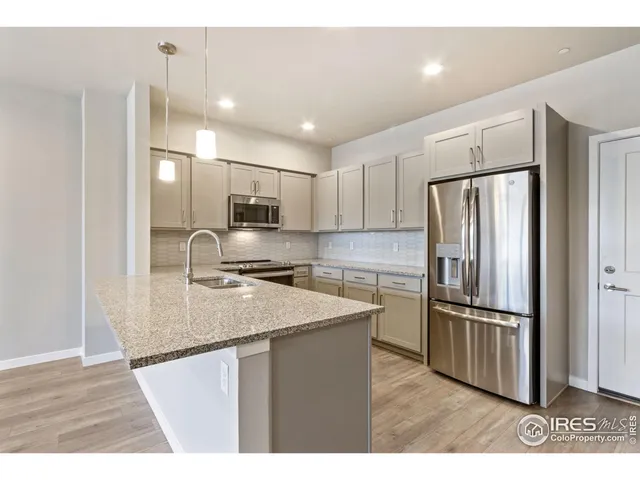 a kitchen with stainless steel appliances granite countertop a refrigerator a sink a stove a microwave and wooden floor