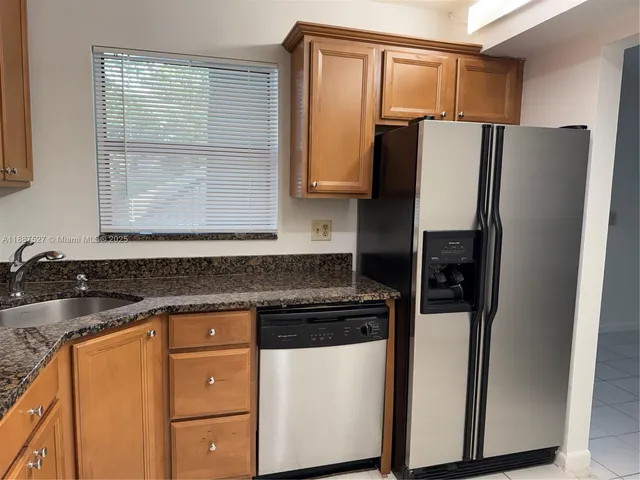 a kitchen with granite countertop cabinets and refrigerator