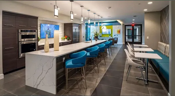 a kitchen with stainless steel appliances kitchen island granite countertop a table chairs sink and cabinets