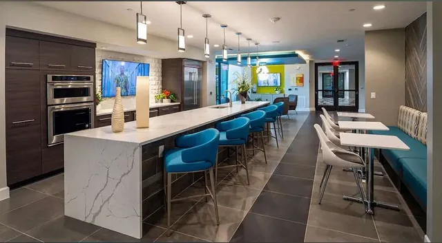 a kitchen with stainless steel appliances kitchen island granite countertop a table chairs sink and cabinets