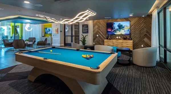 a room with furniture pool table flat screen tv and windows