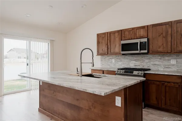 a kitchen with stainless steel appliances granite countertop a stove a sink and a microwave